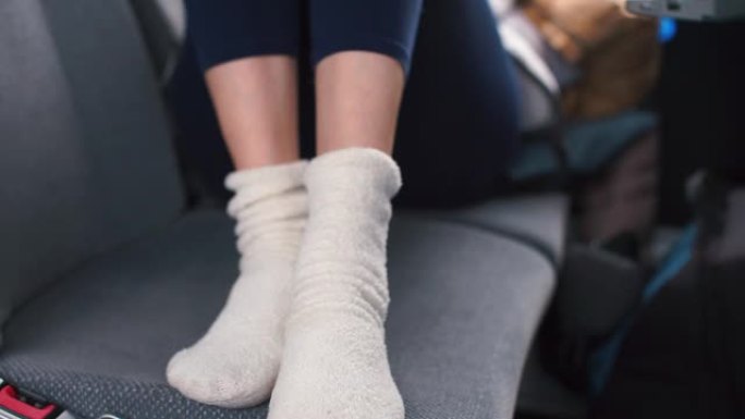 穿着白色袜子的腿的特写镜头躺在公共汽车的乘客座位上。