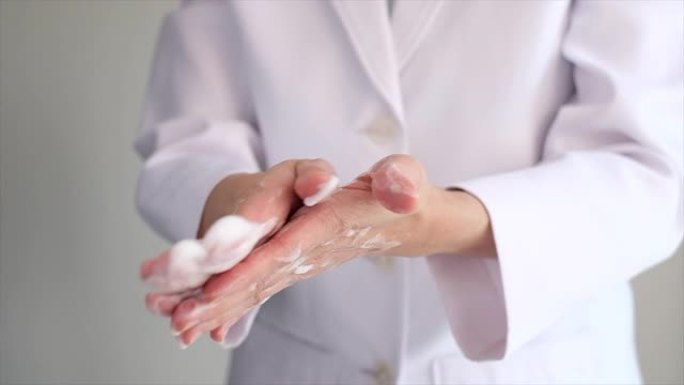 医生用泡沫肥皂洗手，以清洁电晕病毒，细菌和细菌。白色制服背景。特写。洗涤是防止covid19传播的方