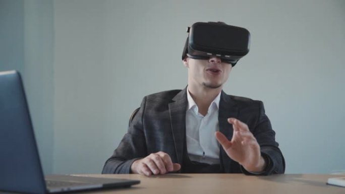 美国设计师在办公室使用笔记本电脑在餐桌上使用vr眼镜获得虚拟体验
