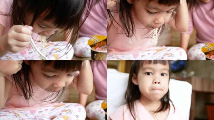 亚洲小女孩在家里用塑料杯吃面条玩得开心。垃圾食品概念。