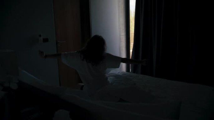 一名年轻的白人女性旅行者醒来并打开遮光窗帘