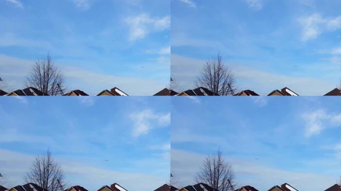 飞机在蓝天上飞过住宅建筑物的远景。商用飞机在城市屋顶上飞、上升和爬升。