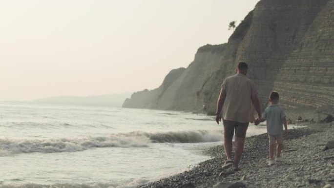 一个男人和一个男孩沿着卵石滩散步的背景图