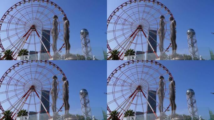 摩天轮与巴统堤岸上的阿里和尼诺雕像在蓝天上