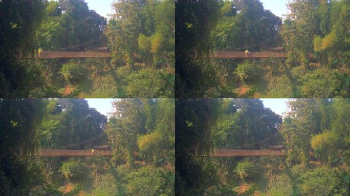 摩托车越过小河上的悬索桥的侧视图