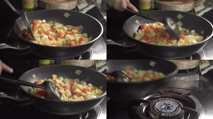 厨师在平底锅里炒菜，然后吃完。胡萝卜、土豆、洋葱放在平底锅上。