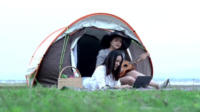 两个快乐的女孩在露营现场演奏夏威夷四弦琴，听唱歌