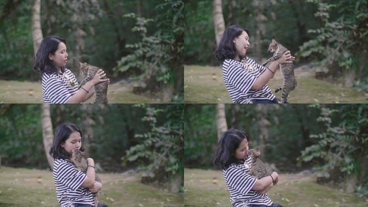 年轻女子在大自然中与猫玩耍。