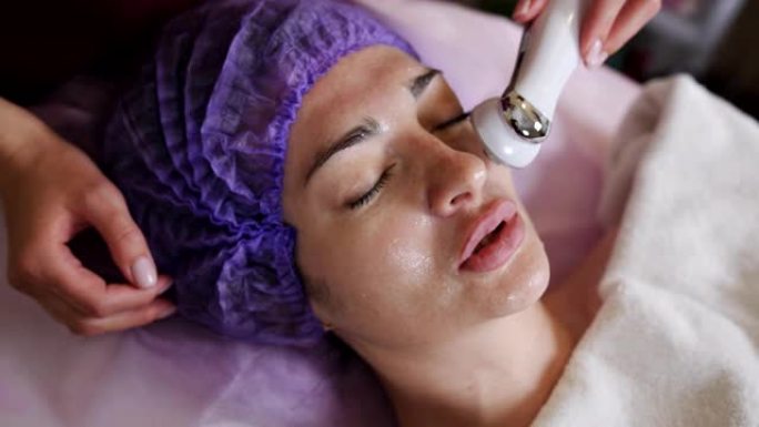 美容和技术概念-美容师用微晶换肤装置对躺在水疗中心的年轻女子进行面部去角质
