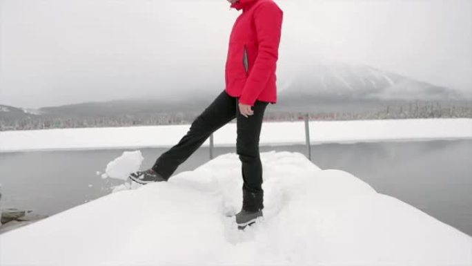 女人在朱红色湖踢雪球