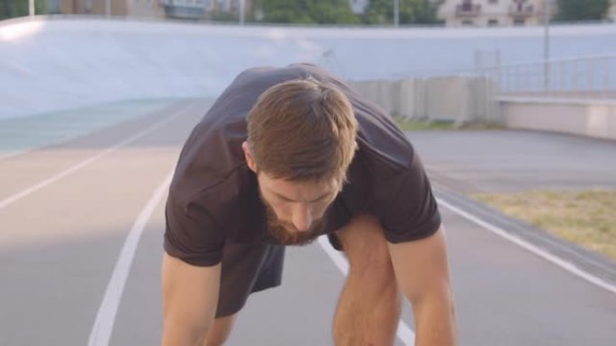 成人高加索运动男性慢跑者的特写肖像准备在城市户外的体育场上跑步