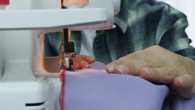 职业女裁缝在缝纫机上工作。在裁缝工作室里，女性手缝布料的特写镜头。创造和剪裁服装。手工服装的女人