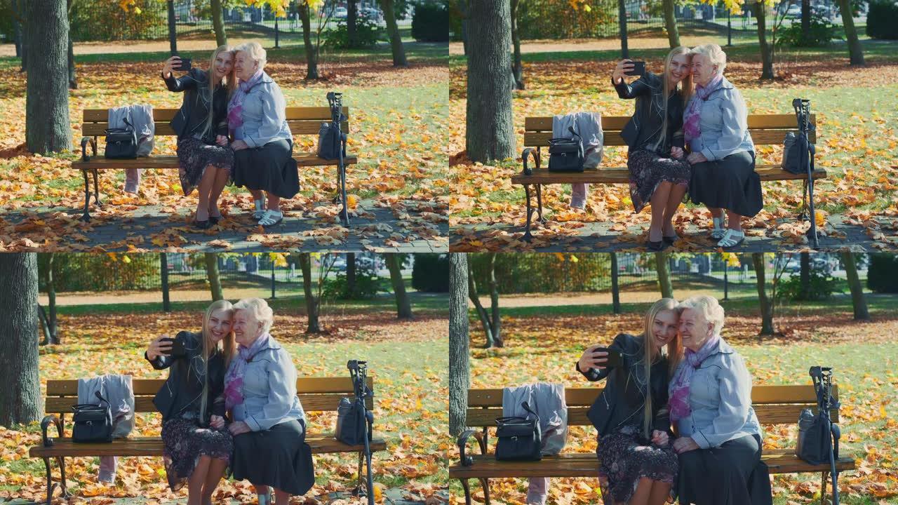 秋天在美丽的公园里，年轻人和老年妇女在智能手机上自拍的变焦镜头