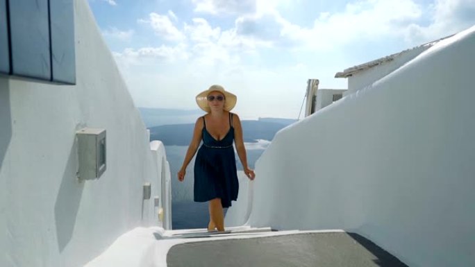 穿着绿色连衣裙和太阳帽的幸福女人在希腊圣托里尼岛享受假期。从伊梅罗维格利看破火山口和爱琴海。