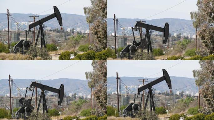 工业城市景观。洛杉矶的拉布雷亚·英格尔伍德。井泵千斤顶在栅栏后面运行。钻机开采原油。带工作活塞的采油