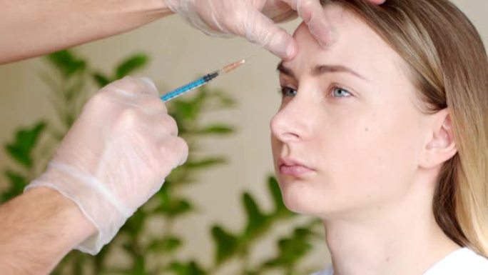 专业美容师的手在女性额头上注射肉毒杆菌毒素