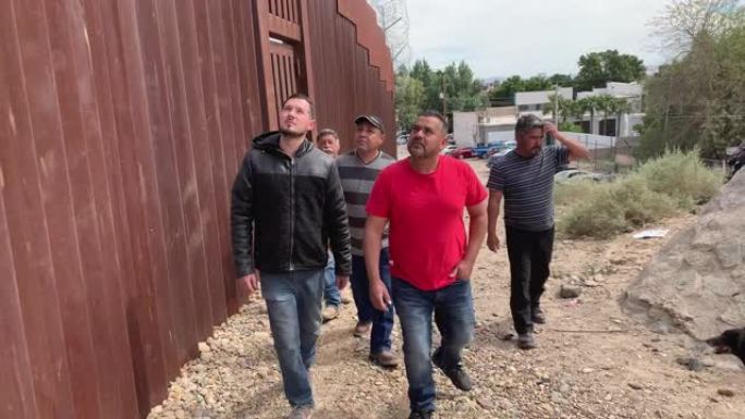 一群四名墨西哥男子站在墨西哥尤马亚利桑那州边境的边境围栏附近