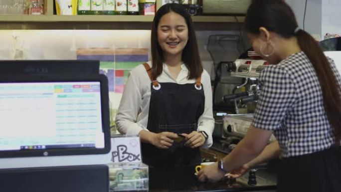 咖啡师服务顾客和女人在咖啡店用信用卡支付咖啡