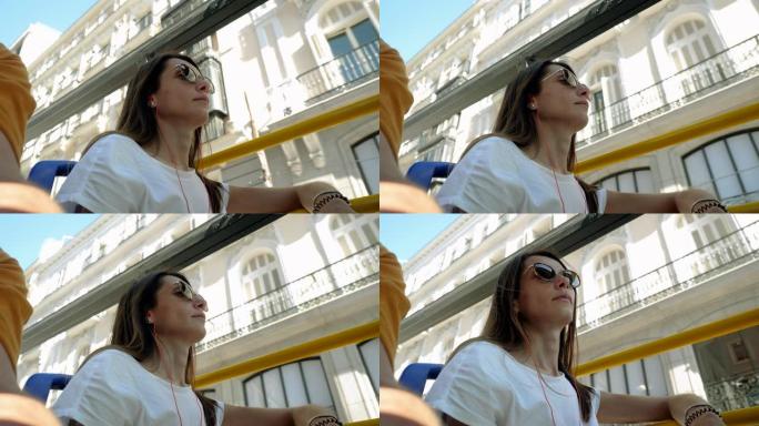 在夏天阳光明媚的日子里，年轻美丽的女人在乘坐旅游巴士环游城市时看着马德里的风景。西班牙。4K