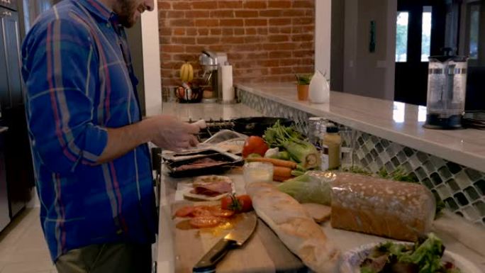 男人在他的家庭厨房里用切成薄片的熟食肉做三明治