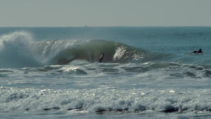 冲浪者在蓝色的大海中骑着巨大的完美波浪的美丽景色。