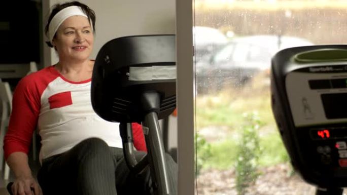 中年妇女在健身房或健身中心的文具自行车上进行有氧运动