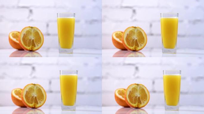 鲜榨橙汁放在桌子上的玻璃杯中，旁边有橙片。白色背景上有水果的清爽黄色饮料