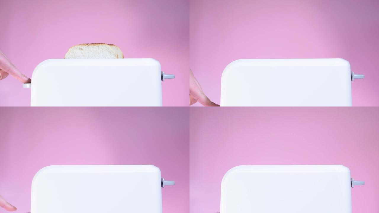 制作烤面包，使用烤面包机厨房在厨房准备早餐。粉红色背景上的白色烤面包机