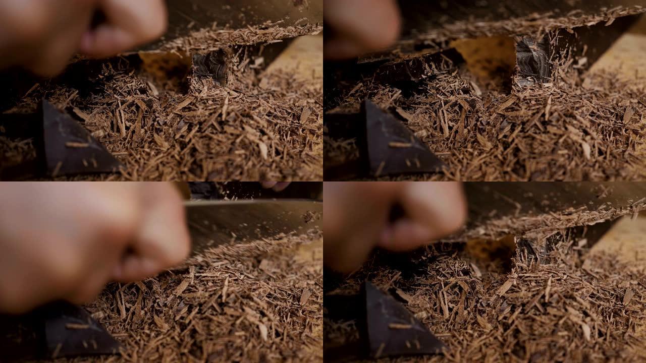 厨房板上切碎的黑巧克力。烘烤时切碎一块巧克力。慢动作。特写。在木制桌子上的砧板上切碎巧克力。特写。