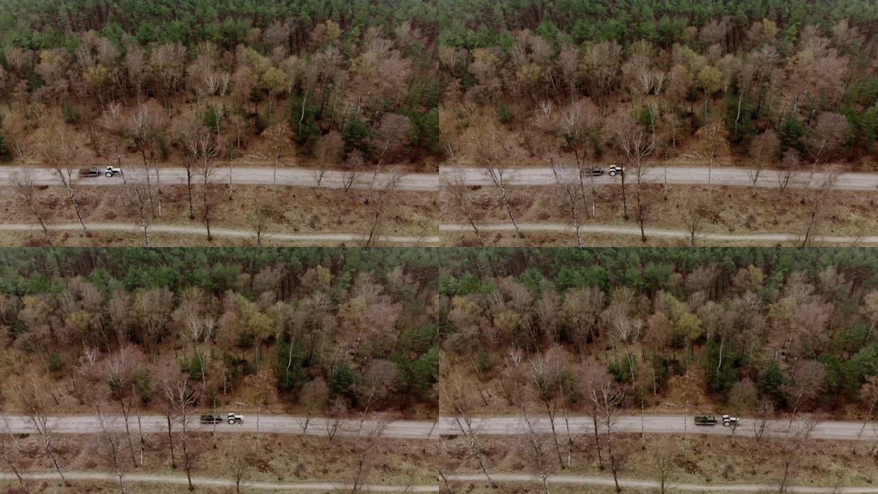 一辆拖拉机从左到右在森林的一条土路上行驶的高角度无人机拍摄，带有复制空间，