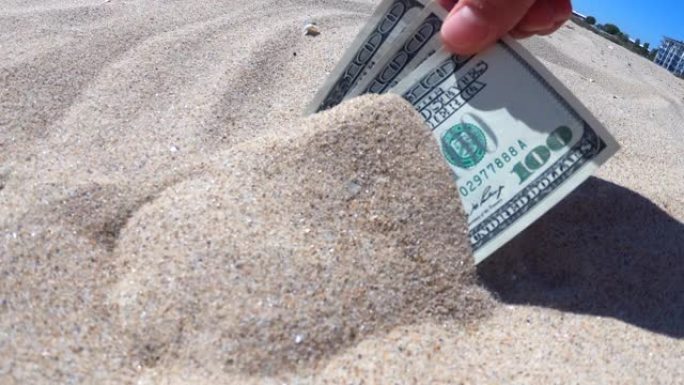 一个女孩从沙子上拿出300美元的钞票