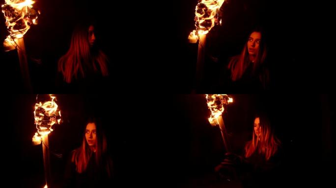 年轻女子手持火把晚上在黑暗的森林中行走