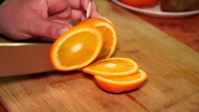 木板上的女孩用刀切开成熟多汁的维他命橙