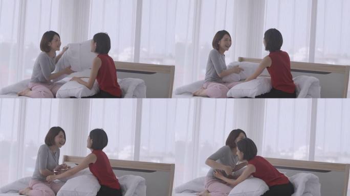 快乐的亚洲女性在床上享受枕头大战。