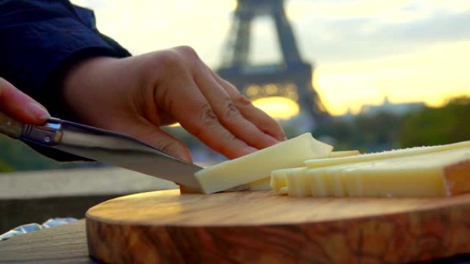 在埃菲尔铁塔的背景上切下硬奶酪的刀