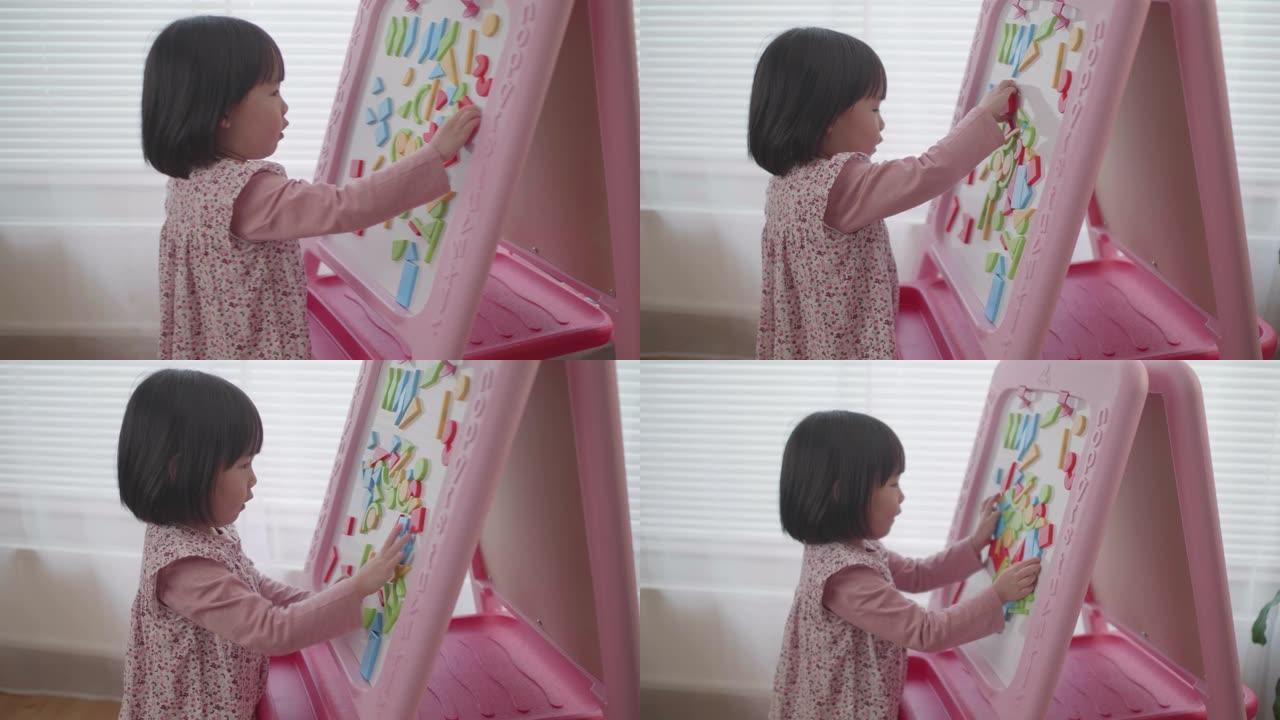 蹒跚学步的女婴在白板上玩形状玩具积木