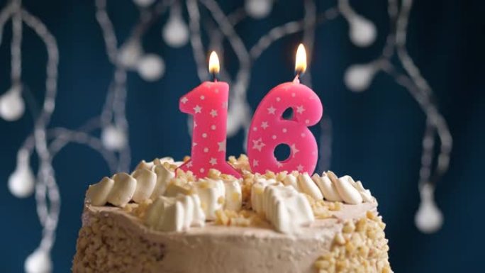 蓝色背景上有16号粉色蜡烛的生日蛋糕。蜡烛吹灭了。慢动作和特写视图