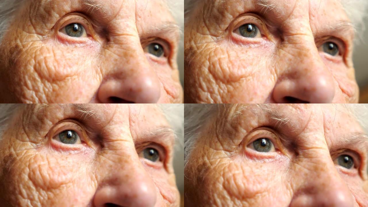 老年妇女看着沉思的肖像。女性脸上有皱纹的特写。祖母平静地望着远方，表现出悲伤或孤独的情绪。细节视图慢