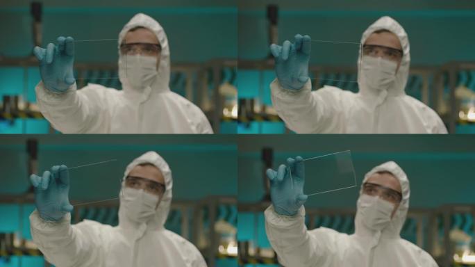 专业医生生物化学家拿着和看方形玻璃。现代实验室中穿着白色防护服的男科学家肖像。男子研究员手里拿着玻璃