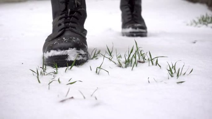 男人穿着沉重的靴子，有力地踏在草地和雪地上