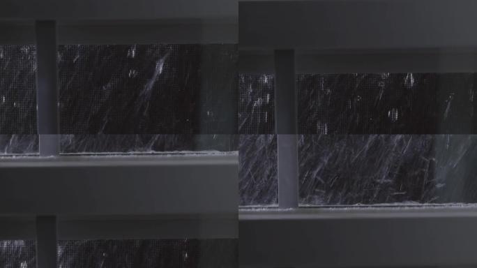 窗户上的雨滴。在倾盆大雨期间，水滴和溪流沿着玻璃流下。