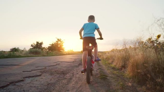 一个孩子在乡间小路上骑自行车。儿童骑自行车。活跃的暑假。