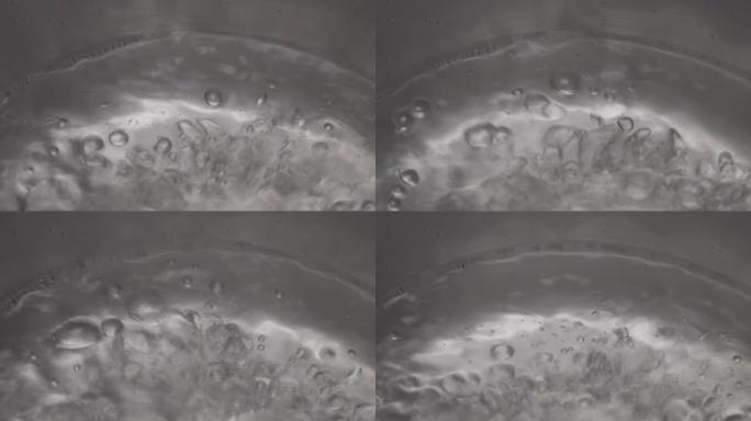 开水过程的宏观拍摄。金属锅中带有气泡的蒸汽水的特写镜头