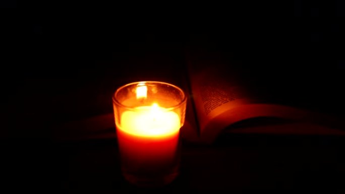 黑暗中的烛光背景中的圣经