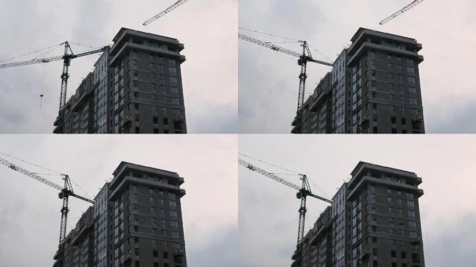 摩天大楼建筑工地上的高起重机。绿区公寓楼建设。正在建设中的带起重机的高层住宅综合体