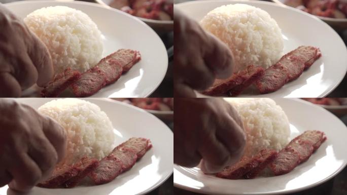 有人在米饭周围装饰红色猪肉。用米饭在酱汁中制作叉烧红猪肉。泰国菜。