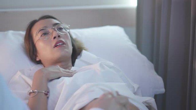 一名亚洲女性孕妇躺在床上，一名女医生在医院诊所扫描婴儿时发出超声波