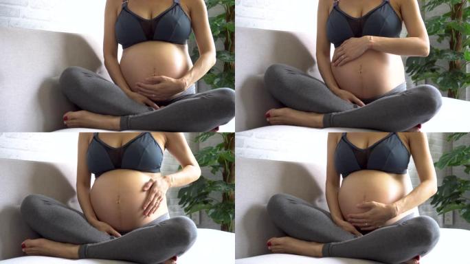穿着运动服的快乐亚洲孕妇触摸肚子里的婴儿