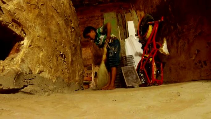 印度小男孩在瓦拉纳西的角落里扫帚破旧的房间自行车和木板