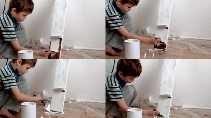 一个5岁的男孩用白色油漆在架子上涂漆。白色背景。
